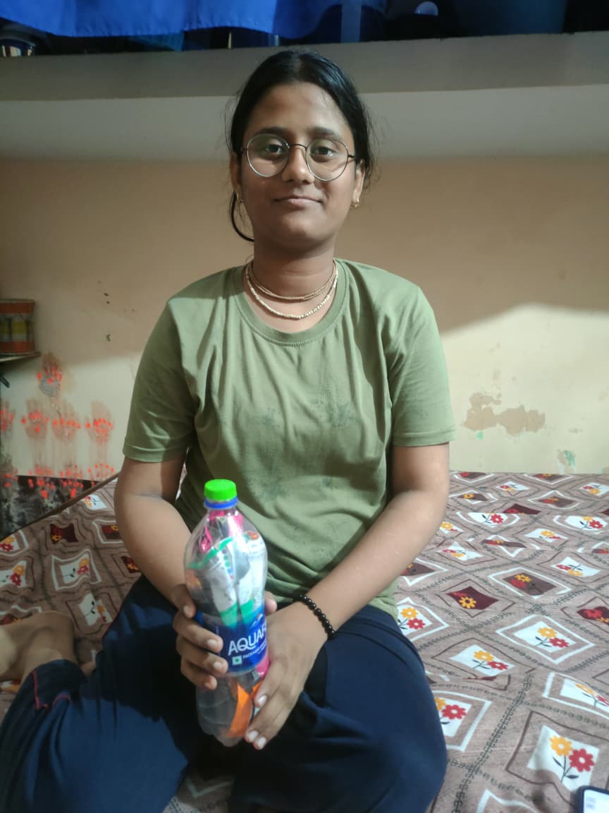 A local student holds a bottle packed with recovered plastic.